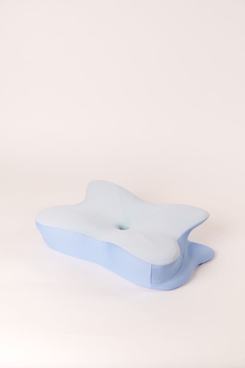 Three-quarter studio view of a contoured memory foam pillow, showing the raised side bolsters and the lower centre well